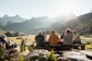 A group of hikers enjoying lunch at an outdoor table in a valley.